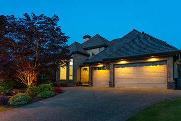 Garage door in luxury house with trees and nice landscape in Spring in Vancouver, Canada, North America. Night time on April 2025.