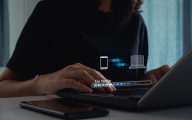 Woman transfer data from mobile phone to laptop. Cloud based file storage, secure data backup...