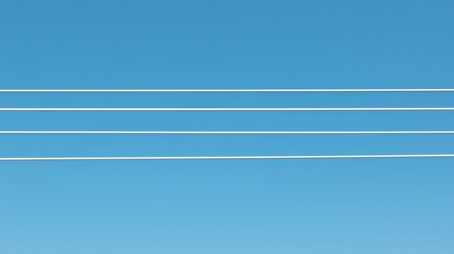 Four parallel power lines stretch horizontally across a clear blue sky.