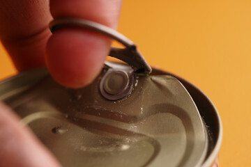 Opening a can with a finger on a bright yellow background