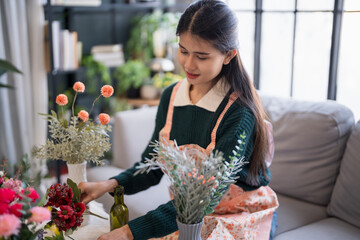 Happy asian Woman arranging flowers caring for home greenery