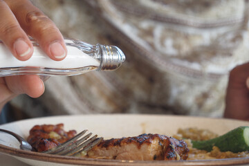 Salt being added to grilled chicken dish at a casual dining setting