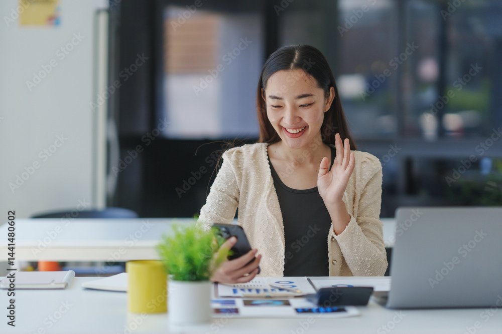 Poster young happy manager smiling and waving while making a video conference using mobile phone in the wor