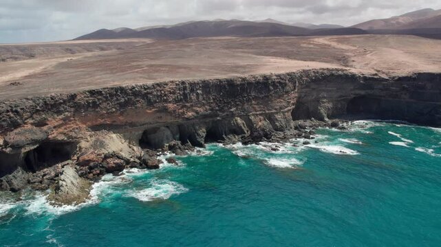 Discovering the Ajui Caves on the island of Fuerteventura from the air, where waves crash against the shore. Canary Islands, Spain.