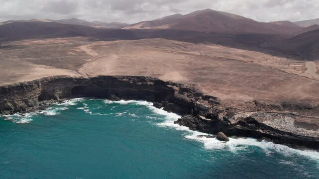 Discovering the Ajui Caves on the island of Fuerteventura from the air and at high altitude, where waves crash against the shore. Canary Islands, Spain.