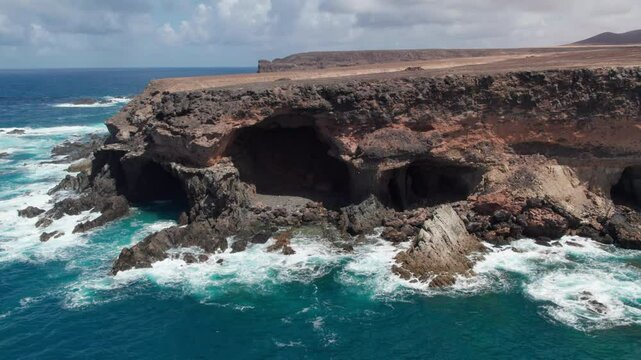 Drone footage circling over the Ajui Caves on the island of Fuerteventura, where the ocean meets the shore. Canary Islands, Spain.