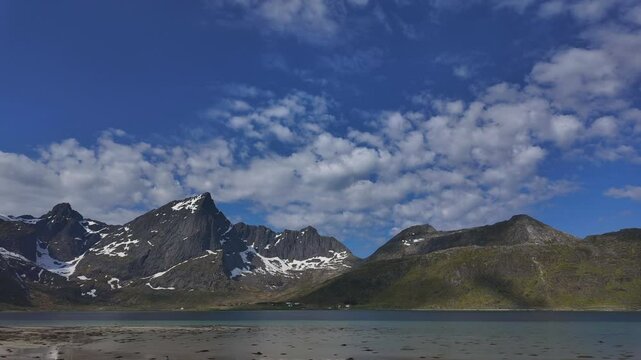 Beautiful time-lapse of the beautiful Morpheus Beach in the Lofoten Islands with snow-covered mountain peaks and moving clouds.