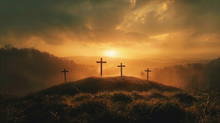 Obraz premium Four wooden crosses on a grassy hill at sunset with misty hills and dramatic cloudy sky creating a peaceful and solemn atmosphere