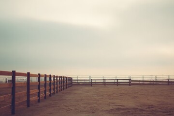 captured at dusk vast empty rodeo arena with wooden fencing enclosure stands under muted sky