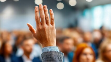 A hand raised in an auditorium setting, symbolizing a response or engagement of people.