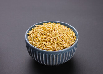 Indian snacks called Bhujia Sev or Medium Sev serve in bowl isolated on dark Background 