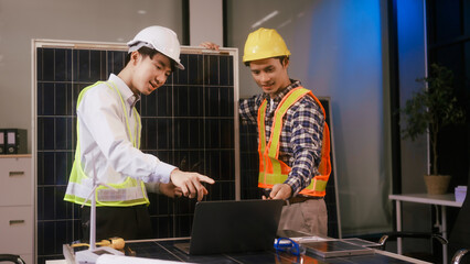 Two Asian businessmen wearing engineer hats table, discussing solar panels and wind turbines. They...