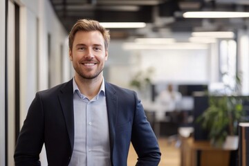 Fototapeta premium Portrait of a smiling man in a suit standing in an office environment with a blurred background