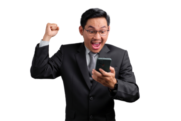 Excited Asian businessman celebrating success with fist raised and looking at smartphone, isolated on transparent background