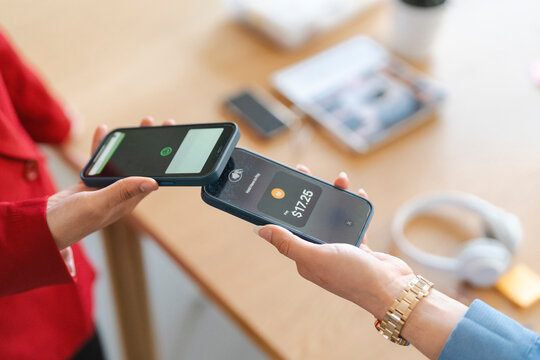 Two people are using their phones to make a tap to pay mobile contactless payment.