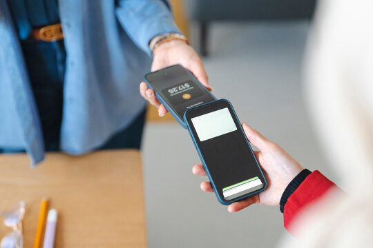 Two people are using their phones to make a tap to pay mobile contactless payment.