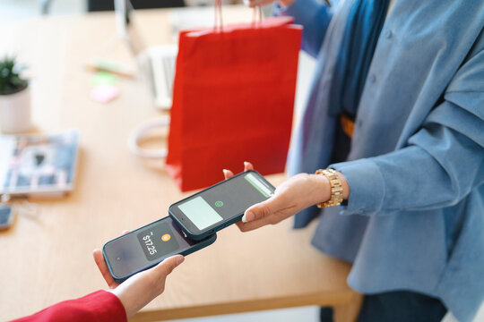 Shopping made easy! A customer is paying for their purchase with a phone tap. It's a modern and efficient way to shop.