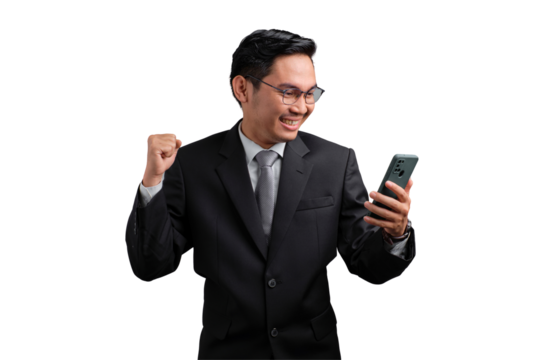 Excited Asian businessman celebrating success with fist raised and looking at smartphone, isolated on transparent background