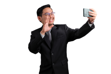 Smiling Asian businessman in suit taking selfie and waving with smartphone, isolated on transparent background