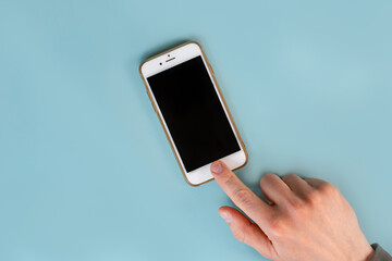 The man's hands are holding a smartphone with a black screen on a blue table background. Close up, point of view shot.