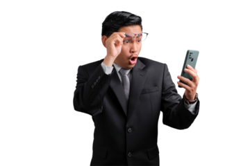 Surprised Asian businessman in suit adjusting glasses and looking at smartphone, isolated on transparent background