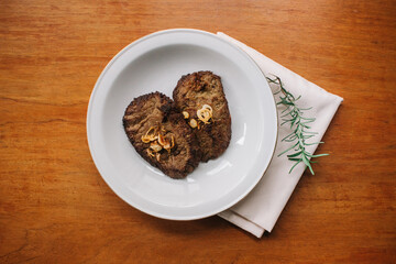 empal gepuk, indonesian style sweet and spicy fried beef dish on white plate and wooden background