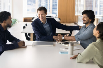 Two multiethnic laughing businessmen greeting each other with handshake, showing respect and camaraderie, conclude agreement, starting collaboration, building strong, lasting business relationships