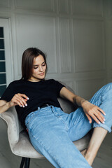 brunette woman posing in photo studio and smiling while sitting on chair