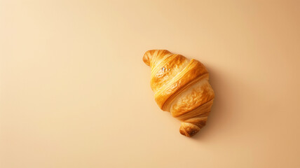 Flaky croissant resting on a warm soft peach canvas with clear margins for text

