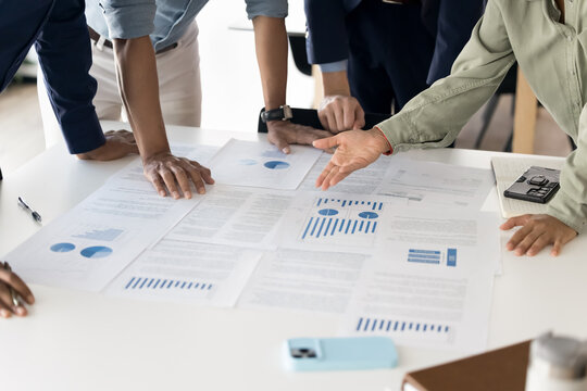 Marketing department having team discussion, work on project strategy, preparing reports, pointing at infographic placed on meeting table, analyzing sales result, do marketing research, close up view