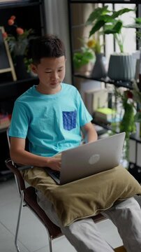 Asian boy studies online on laptop at home