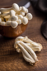 Raw white shimeji mushrooms on wooden table.