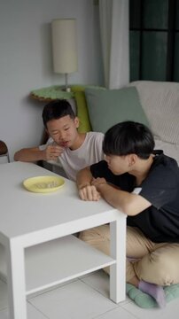 Brother sitting and eating snacks at home.
