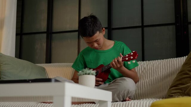 Asian boy learning to play ukulele