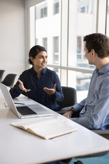Indian professional woman explaining project details to colleague, describing goals, progress,...