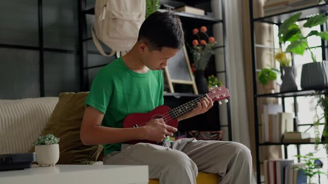 Asian boy learning to play ukulele