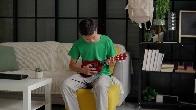 Asian boy learning to play ukulele
