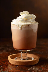 Hot chocolate with whipped cream in a glass mug.