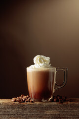 Coffee and chocolate drink with whipped cream on a brown background.