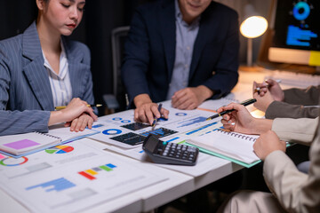 A group of people are sitting around a table with papers and calculators
