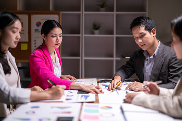 A group of people are sitting around a table with papers and pens