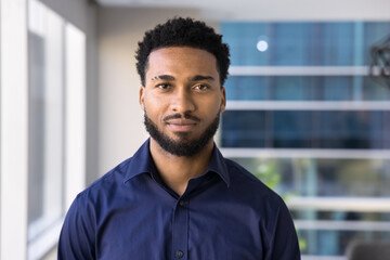 Head shot close up portrait of African businessman dressed in casual dark blue shirt posing in modern workspace with confidence, exude professionalism and competence. Boss or manager profile picture