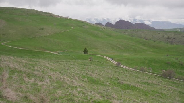Slow Motion of Green Pastures on Hills with Mountains and Dark Clouds