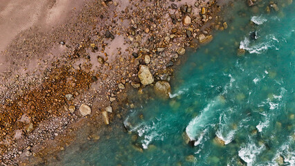 Aerial view of the turquoise river meeting rocky shores