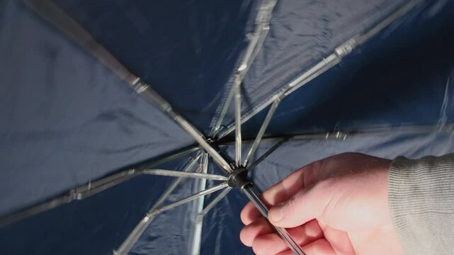 Opening and closing of a mechanical umbrella of dark blue color. Inside view