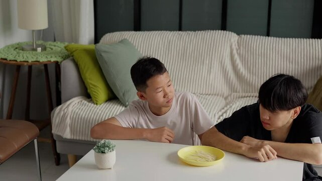 Brother sitting and eating snacks at home.