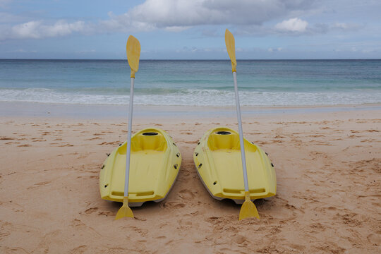 Kayaks resting on sandy beach near calm ocean under cloudy sky