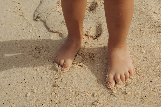 Child's bare feet on sandy beach enjoying warm sunshine