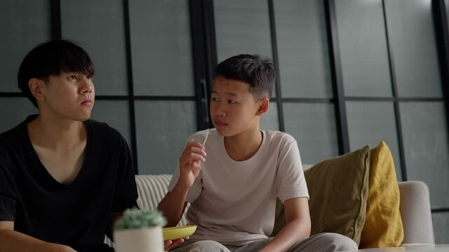 Brother sitting and eating snacks at home.