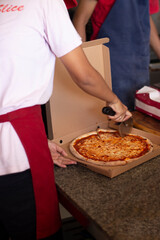 Hand Slicing Margherita Pizza in Box Before Delivery